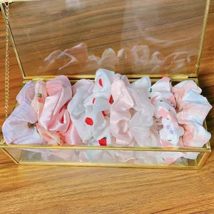 Set di elastici per capelli in raso presentati in un elegante portagioie in vetro