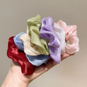Dettaglio di sette elastici scrunchie in organza colorata con trama satinata e pieghe