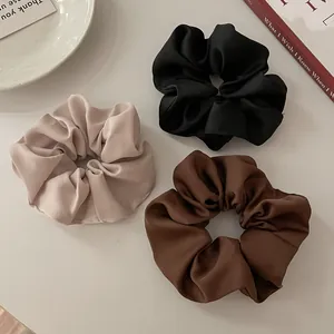 Set van drie satijnen scrunchies in champagne, zwart en bruin met een gladde textuur