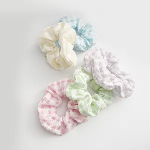 Flat lay of five checkered scrunchies in pastel macaron colors with seersucker texture