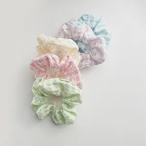 Detailed macro view of four pastel plaid scrunchies with soft seersucker fabric texture