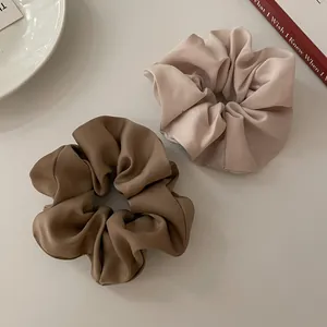 Detail van satijnen scrunchies in koffie en beige op een minimalistische achtergrond