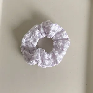 Detail of light purple and white checkered scrunchie with soft pleated fabric texture