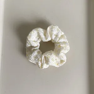 Close-up of cream plaid fabric scrunchie texture with elastic band for hair styling