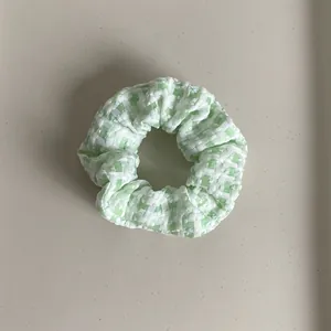Macro detail of green and white plaid fabric scrunchie showing soft textured pleats