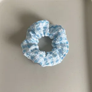 Detailed close-up of blue and white plaid fabric texture on a soft pleated scrunchie