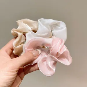 Dettaglio di elastici in organza crema, bianco e rosa che mostrano trama e lucentezza