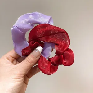 Primo piano di elastici scrunchie in organza lilla e rosso scuro con trama jacquard