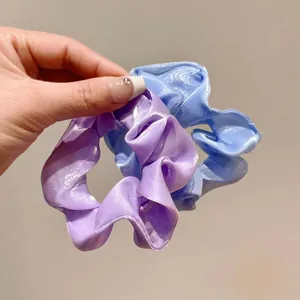 Dettaglio di elastici scrunchie in organza lilla e blu con trama plissettata e luccicante