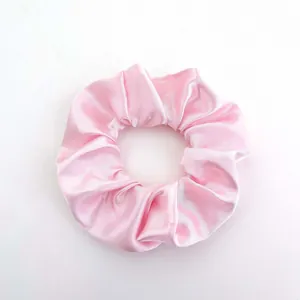 Detailed view of pink satin scrunchie with soft pleated texture and glossy fabric finish