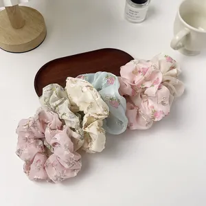 Five-piece floral organza scrunchie set in pastel colors on a rustic wooden tray