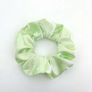 Detail shot of mint green satin hair scrunchie with soft silk luster on white background