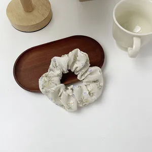 Detail of floral organza scrunchie on a wooden tray with a minimalist aesthetic style