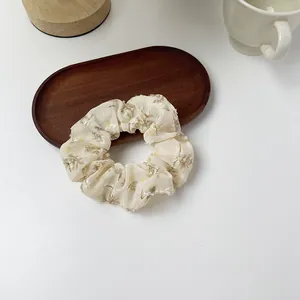 Detail of cream organza floral scrunchie on a dark wooden tray with elegant decor