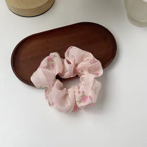 Detail of pink organza scrunchie with floral embroidery on an elegant wooden tray