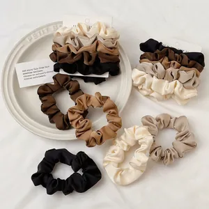 Five-piece satin scrunchies set in neutral earth tones on a soft fabric background