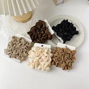Set of five satin silk scrunchies in earth tones displayed on a white aesthetic card