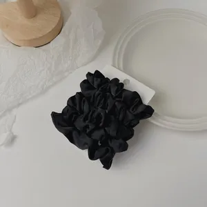 Detail of two black satin scrunchies on a white display card for elegant hair styling