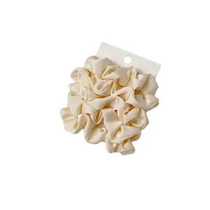 Elegant beige satin scrunchie with pleated texture on white display card for women