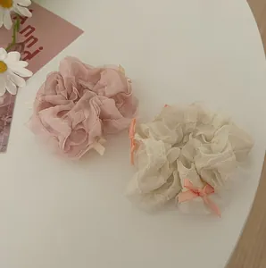 Detail of pink and beige organza scrunchies with sweet bow decorations on white desk