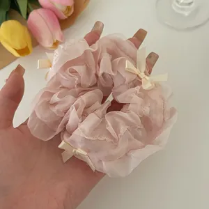 Detail of pink organza scrunchie with lace ruffles and white ribbon bow accents