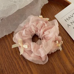 Detailed view of pink mesh scrunchie with lace edges and cream ribbon bows