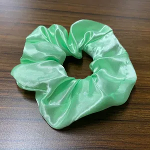 Λεπτομερής όψη του σατέν LED scrunchie σε μέντα πράσινο χρώμα πάνω σε ξύλινο φόντο