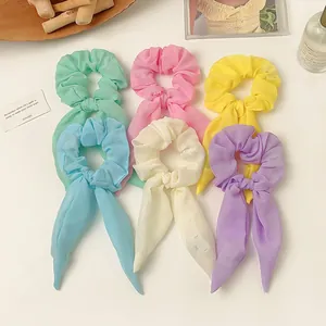 Chiffon-Haargummis in Macaron-Farben mit langen Bändern auf einem weißen Tisch