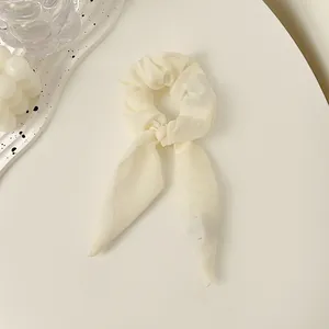 Makro-Detail eines cremeweißen Jacquard-Haargummis mit elegant fließender Bandstruktur
