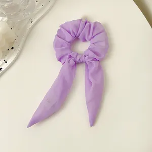 Detailansicht eines hellvioletten Organza-Haargummis mit langen Bändern auf weißem Grund