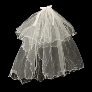 Détail d'un voile de mariée blanc double épaisseur avec nœud en soie et perles sur fond noir