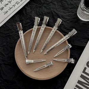 Silver metal hair clips and salon duckbill clamps set on a wooden tray with elegant decor