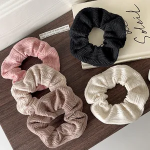 Set of 5 knit scrunchies in neutral tones on a dark wood table background