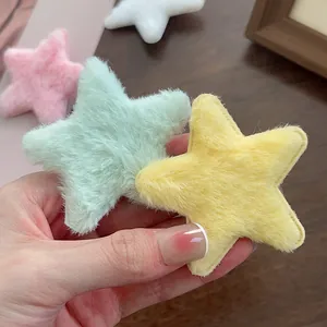 Gros plan de pinces à cheveux étoiles en peluche colorées en menthe, jaune, rose et blanc