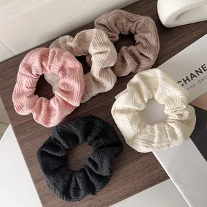 Set of five chunky cable knit scrunchies in assorted neutral tones on a wooden tray