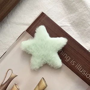 Gros plan d'une pince à cheveux étoile en peluche vert clair avec texture en fausse fourrure