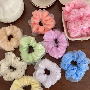 Détail des chouchous en tulle aux couleurs macaron sur une table en bois sous lumière douce