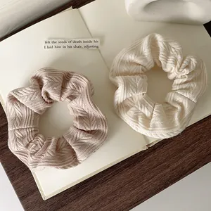 Elegant chunky knit hair scrunchies in cream and pink colors on an open book surface