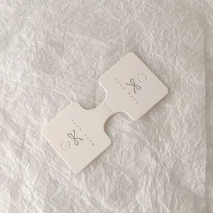 Primer plano de tarjeta blanca para joyas con logo de lazo en papel con textura