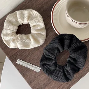 Close-up of knit scrunchies in cream and black featuring detailed cable textures
