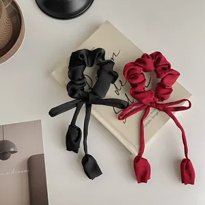 Detail of black and burgundy satin scrunchies with long streamers on vintage books