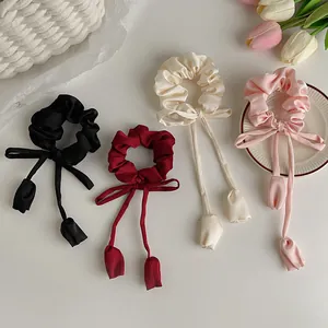 Close-up of four satin scrunchies with long silk streamers in various elegant colors