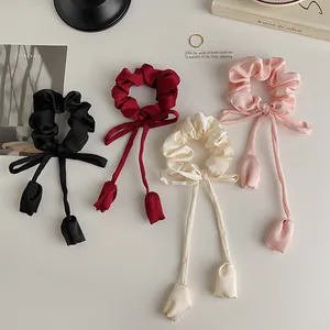 Detailed view of satin scrunchies with long ribbons and tulip charms in four elegant colors
