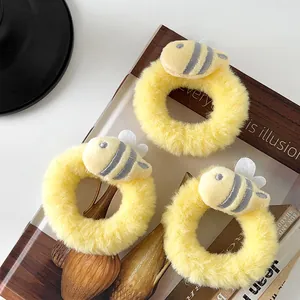 Detailed view of three yellow plush hair ties with cute 3D cartoon bee ornaments