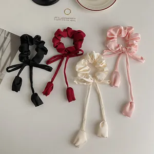 Detail view of satin hair scrunchies with long streamers and tulip bud charms in four colors