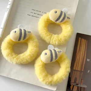Three-piece set of cute yellow plush bee scrunchies on book background for girl hair