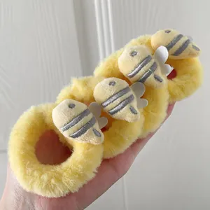 Close-up of four plush yellow hair scrunchies with cute 3D cartoon bee ornaments