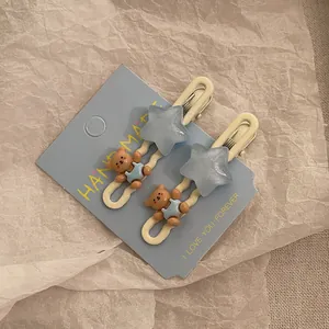 Detailopname van handgemaakte haarclips met beer en blauwe ster op kaart
