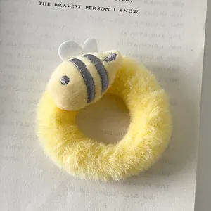 Close-up of a cute yellow plush bee scrunchie with embroidery detail on an open book