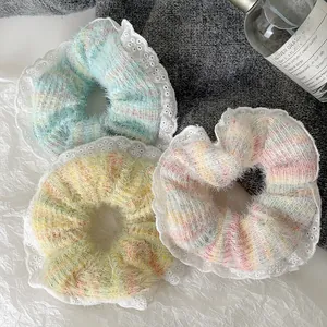 Close-up of three plush lace scrunchies in pastel blue, yellow and pink colors